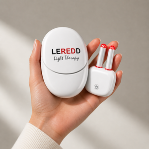 Hand holding a LEREDD LED light therapy NASALED device with its charging and sterilisation case with two red light bulbs on a neutral background