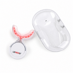 A white LED light therapy device with a clear protective cover and a matching oval charging case, shown on a clean white background. The device is illuminated with a red light, and the brand name 'LEREDD' is visible on the circular base.