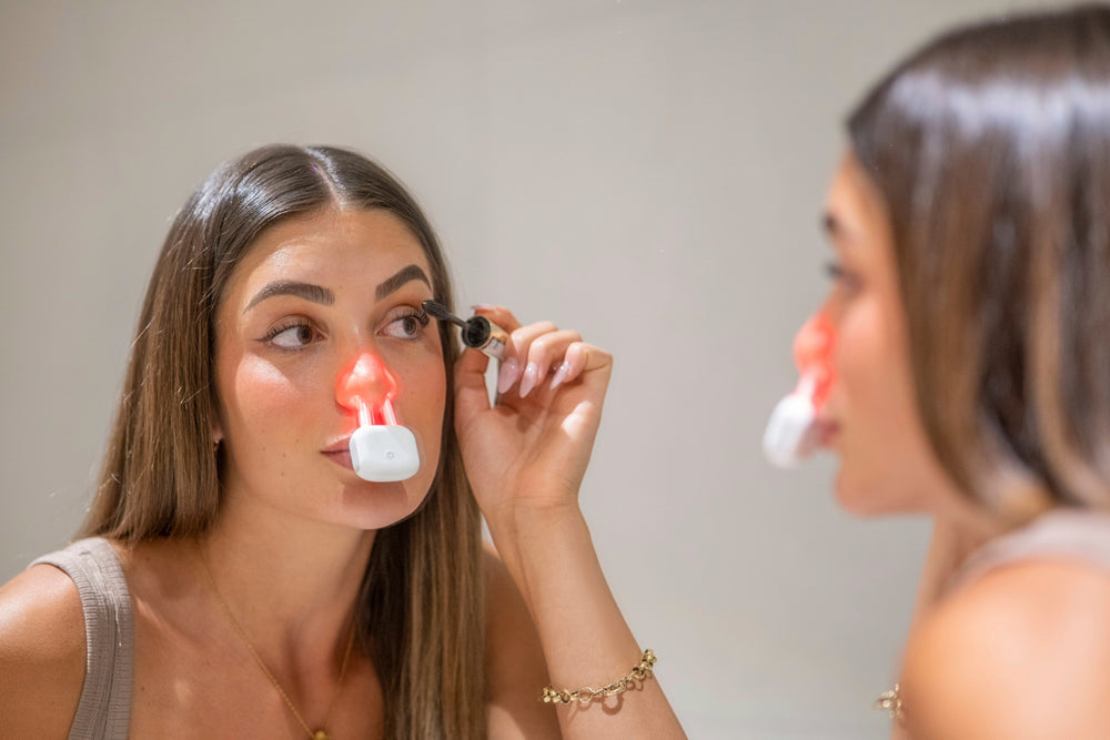 LEREDD light therapy device next to its charging and sterilsation case  for Nasal use  to treat hayfever with two red lights on a white background
